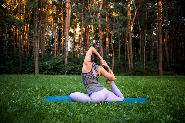 Uma menina morena senta-se e faz yoga na natureza