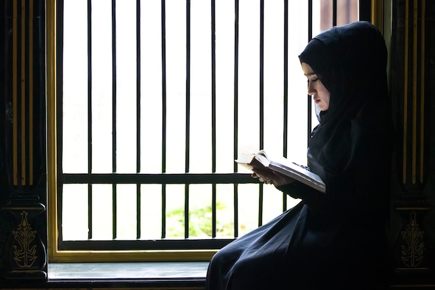 Uma menina muçulmana coloque lenço preto na cabeça estava lendo textos islâmicos. estritamente