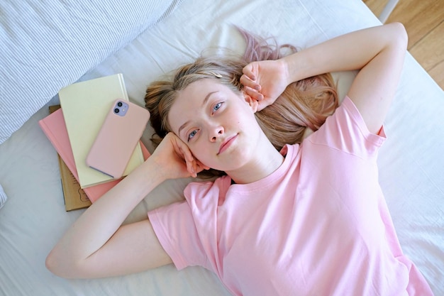 Foto uma menina muito bonita de 15-18 anos de idade está deitada na cama vista de cima