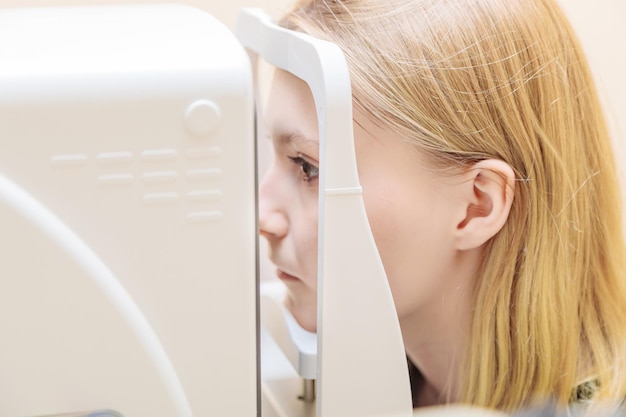 Uma menina na recepção do oftalmologista verifica sua visão com um aparelho especial