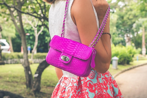 Foto uma menina no parque contra o fundo de árvores tropicais segura uma bolsa feita de pele de pitão