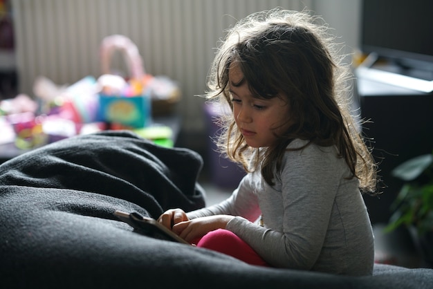 Uma menina olha e usa um telefone inteligente sentado em sua casa