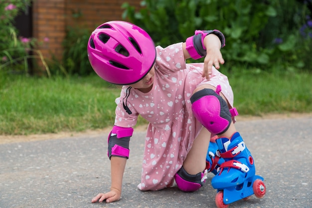 Uma menina patinando em proteção total caiu no asfalto