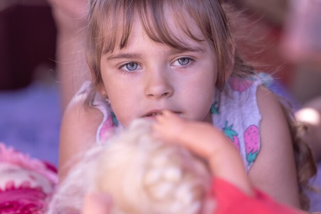 Uma menina pensativa, uma criança deitada ao lado de um brinquedo pronto para chorar
