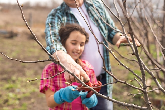 Uma menina pequena com o avô lá fora na natureza da primavera, se divertindo. jardinagem