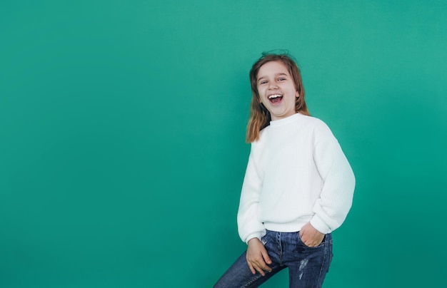 Uma menina pequena e bonita grita alto com a boca aberta sobre um fundo verde isolado.