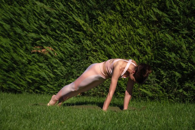 Uma menina pratica ioga na rua, com um agasalho de treino rosa, faz vários exercícios e poses de ioga