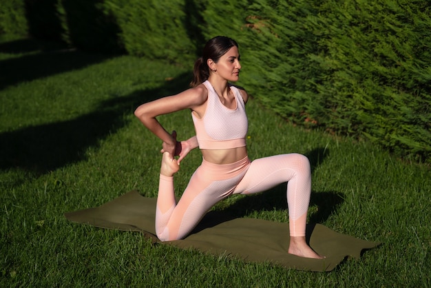 Uma menina pratica ioga na rua, com um agasalho de treino rosa, faz vários exercícios e poses de ioga