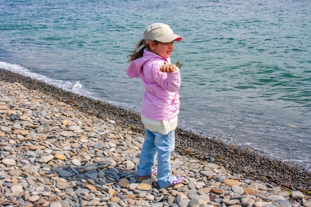 Uma menina pretende jogar uma pedra no mar