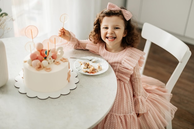 Uma menina rindo come um bolo de aniversário em seu aniversário em casa.