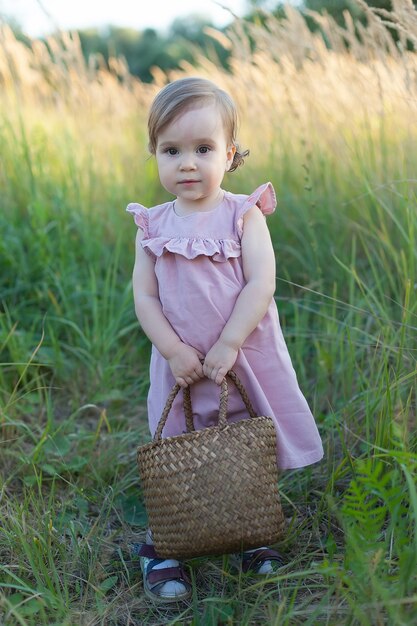 Uma menina rosa em um campo com uma cesta nas mãos. colheita de verão de maçãs e ameixas.