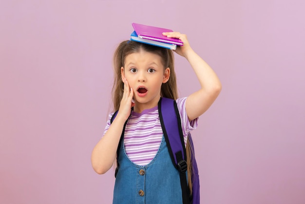 Uma menina segura os livros sobre a cabeça e fica muito surpresa.