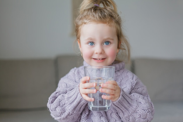 Uma menina segura um copo de água, bebidas. aconchegante.