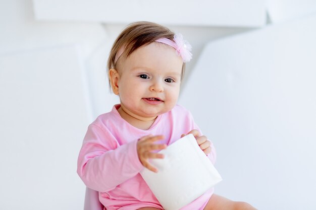 Uma menina senta em um penico e brinca com papel higiênico