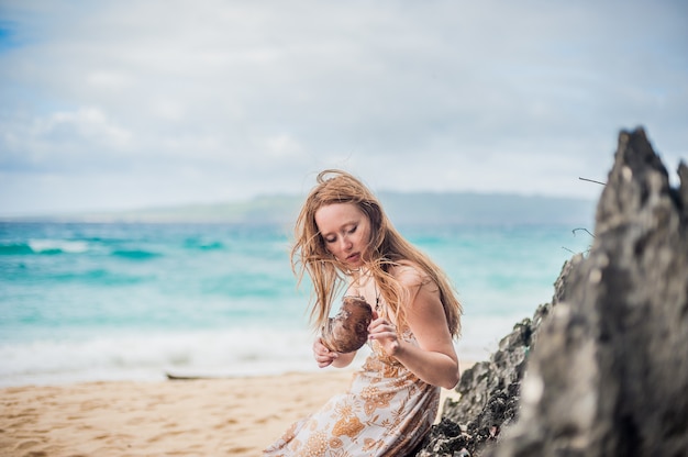 Uma menina senta-se em uma pedra na praia de Boracay