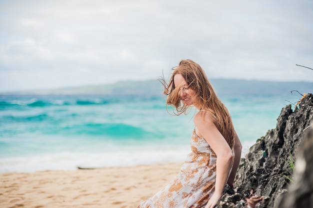 Uma menina senta-se em uma pedra na praia de Boracay