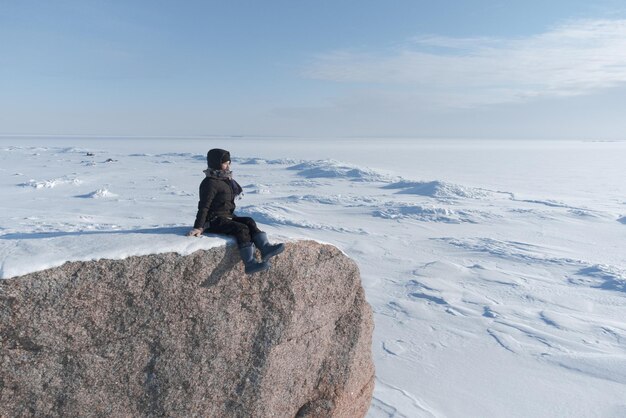 Foto uma menina senta-se na costa de um mar congelado e olha para o horizonte