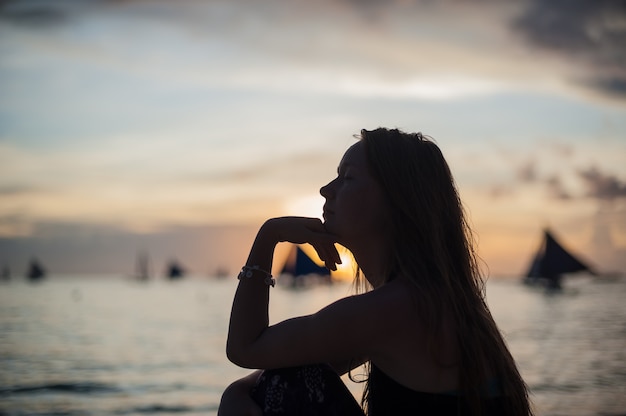 Uma menina senta-se na praia na ilha de Boracay