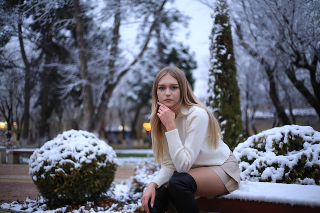 uma menina senta-se num banco na neve