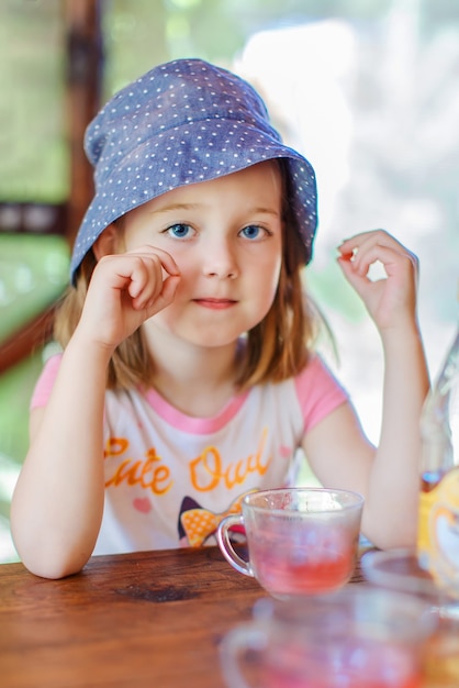 uma menina sentada à mesa no jardim de verão