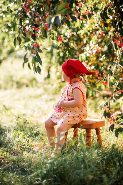 Uma menina sentada em um banquinho de madeira em um fundo de campo de cereja