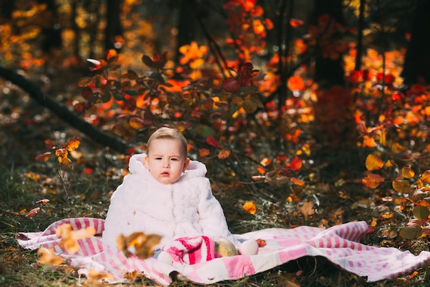 Uma menina sentada em um cobertor na floresta de outono