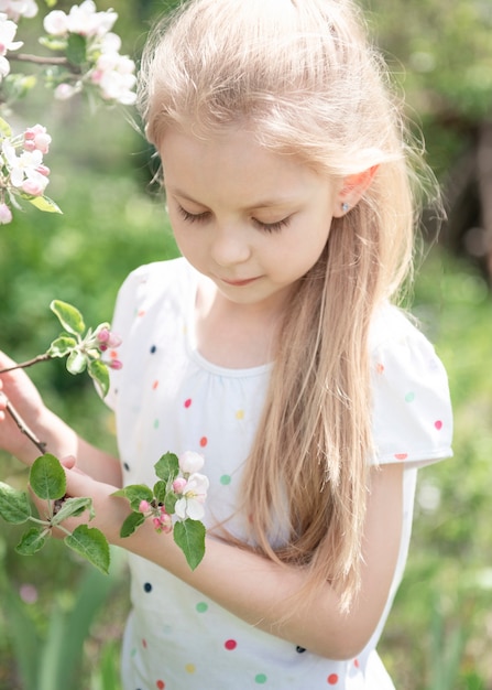 Uma menina sentada em uma árvore em flor no jardim de maçãs