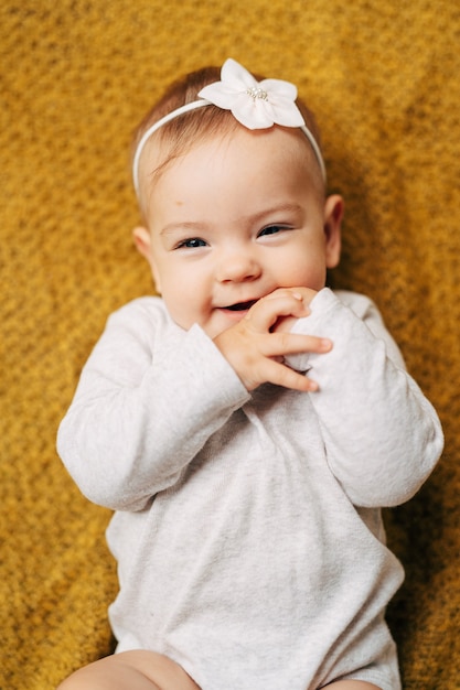 Uma menina sorridente com uma flor na cabeça e uma blusa branca mentindo