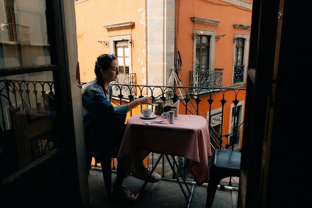 uma menina tem o pequeno-almoço em um café na varanda com vista para a rua México