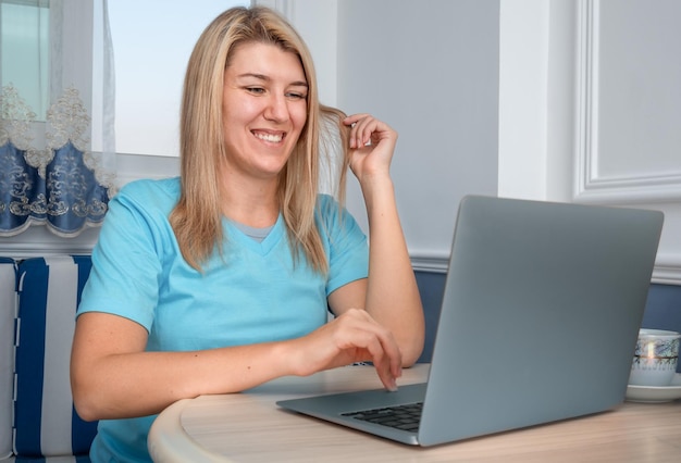 Foto uma menina usa um laptop para se comunicar e senta-se em uma mesa