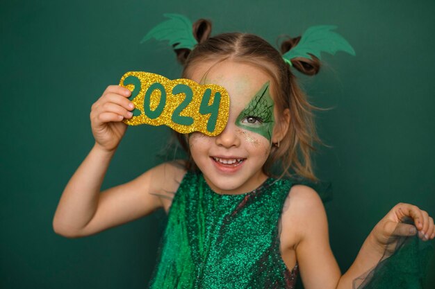 Uma menina vestida como um dragão com um rosto pintado fecha o olho com o número 2024