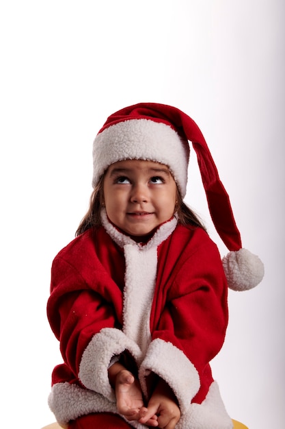 Uma menina vestida de Papai Noel em um fundo branco
