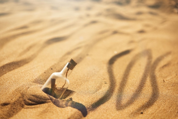 Uma mensagem em uma garrafa lavada em terra sos a palavra em uma praia de areia com uma onda suave