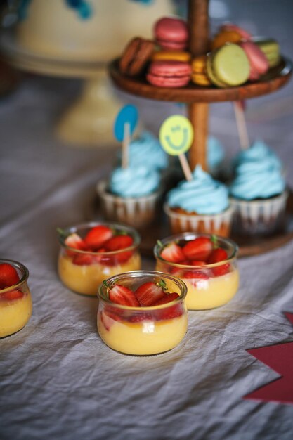 Uma mesa com cupcakes e um suporte para bolos com cupcakes azuis.