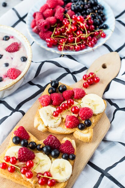 Uma mesa com um pequeno-almoço saudável de verão - aveia com frutas vermelhas, groselhas e framboesas