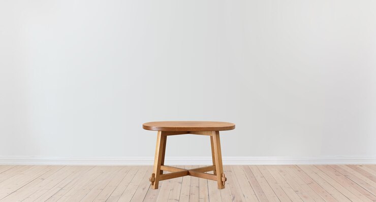 Uma mesa de madeira em uma sala com piso de madeira com uma parede branca atrás dela