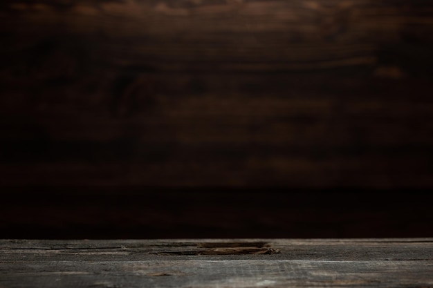 Uma mesa de madeira muito velha e maltratada e fundo de cozinha de parede de madeira escura