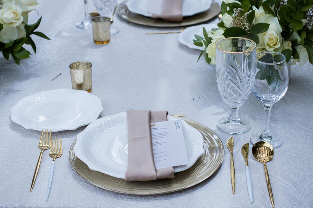 Foto uma mesa definida com um pano de mesa branco e pratos de prata