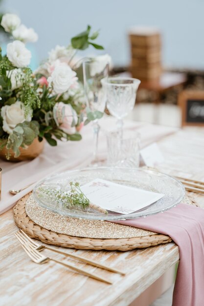 Uma mesa posta para um casamento com uma toalha de mesa rosa e um cartão branco sobre ela.