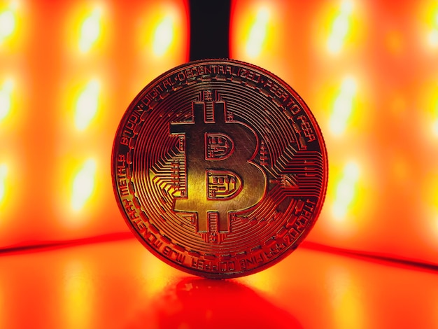 Uma moeda com símbolo bitcoin na luz vermelha. conceito de uma crise do mercado de criptomoedas.