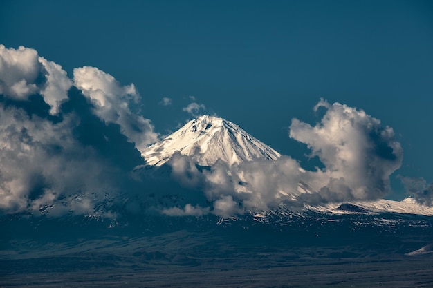 Uma montanha coberta de neve atrás das nuvens