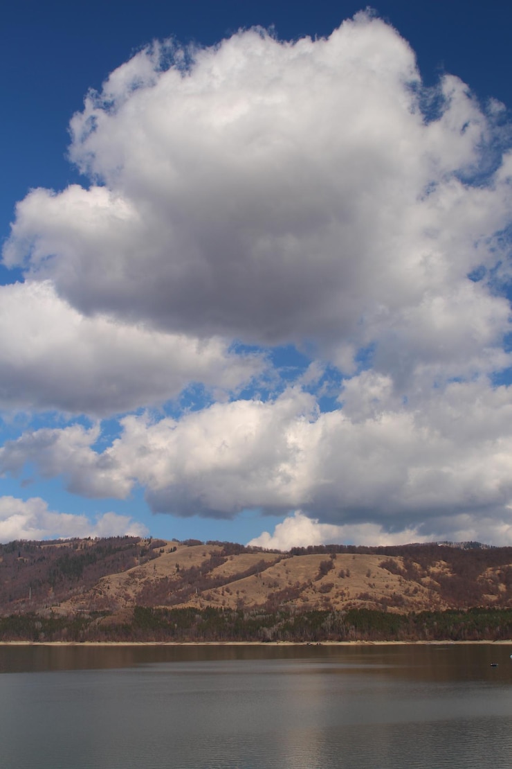 Foto uma montanha é mostrada com um céu azul e nuvens