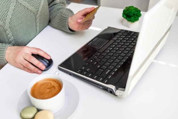 Uma mulher à mesa procura mercadorias na Internet paga por mercadorias