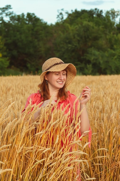 Uma mulher à noite em um campo de trigo examina as orelhas