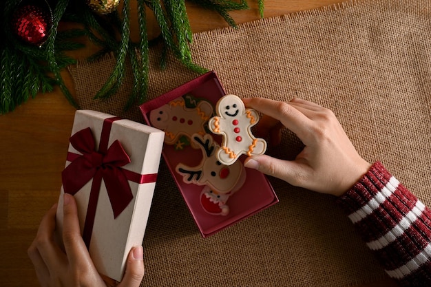 Uma mulher abrindo uma caixa de presente surpresa com biscoitos de gengibre fofos Lanche tradicional de Natal