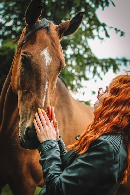 Uma mulher acariciando um cavalo em um campo