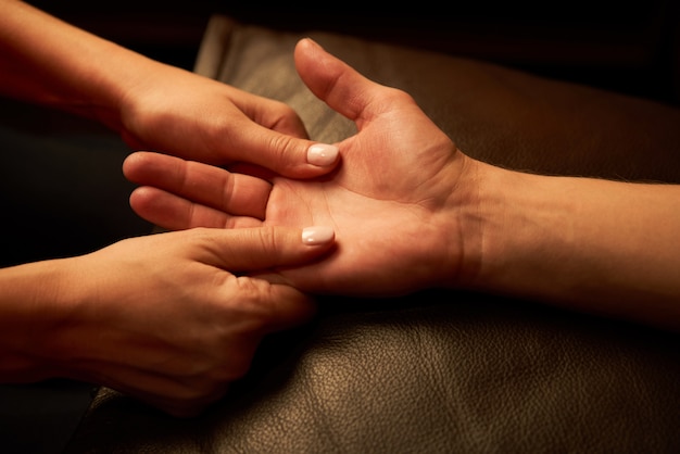 Uma mulher acupressa os dedos para um homem. massagem das mãos com iluminação íntima.