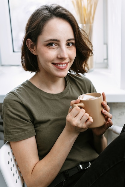 Uma mulher adorável está bebendo uma bebida quente