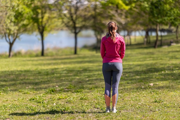 Uma mulher adulta em roupas esportivas em pé no campo vista de trás