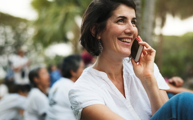 Uma mulher adulta falando ao telefone no parque